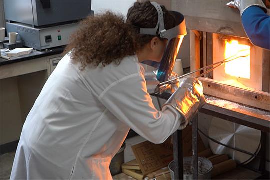 woman placing glass sample in furnace